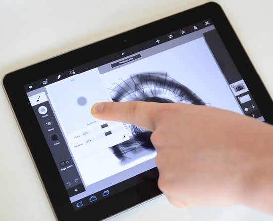 Finger interacting with Adobe Photoshop Touch on a tablet.