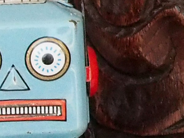 Vintage toy robot next to wooden sculpture