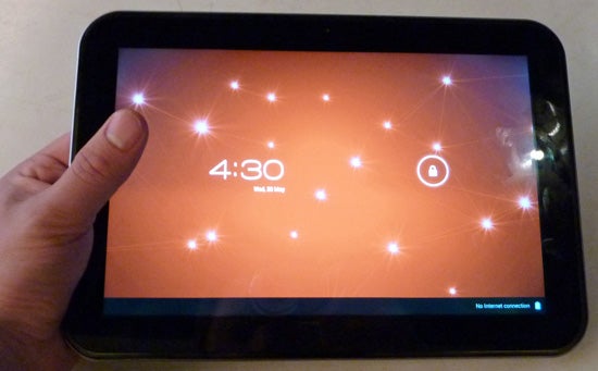 Hand holding Toshiba AT300 tablet displaying lock screen.