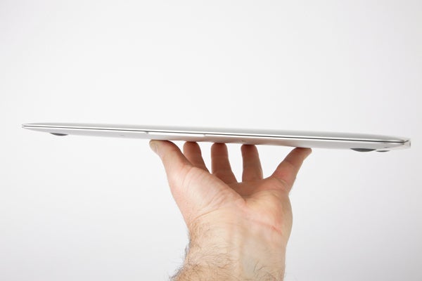Hand holding slim Apple MacBook Air 13-inch laptop from side.