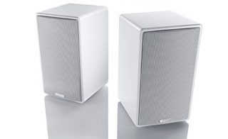 Two white Canton bookshelf speakers on reflective surface.