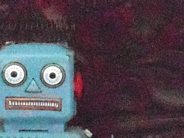 Blurred image of a toy robot with red background.