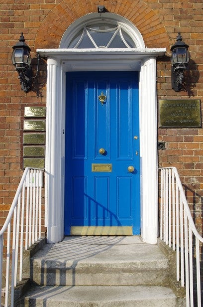 Blue door at entrance of brick building with white steps.