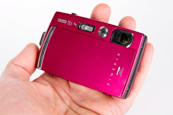 Hand holding a pink Fujifilm FinePix Z1000EXR camera.