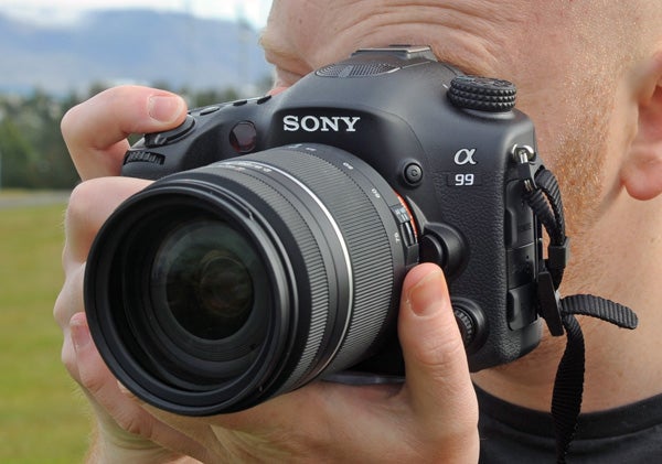 Person holding a Sony Alpha A99 camera for a review.