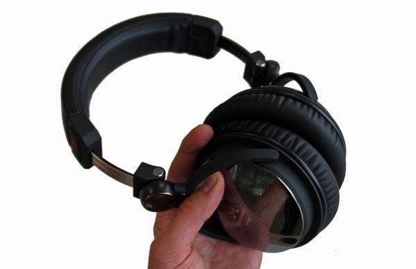 Hand holding SoundMagic HP100 headphones with black earcups