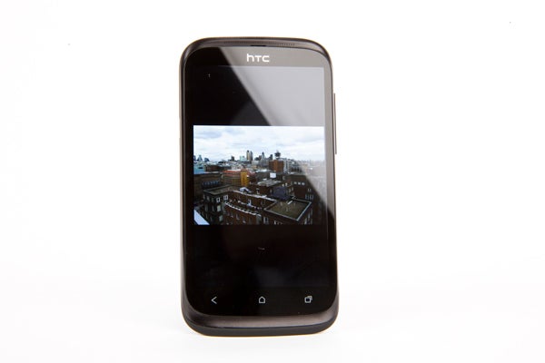 HTC Desire X smartphone displaying a cityscape photo.Hand holding an HTC Desire X smartphone