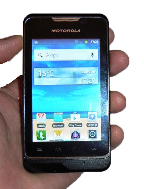 Hand holding a Motorola Motosmart smartphone displaying home screen.