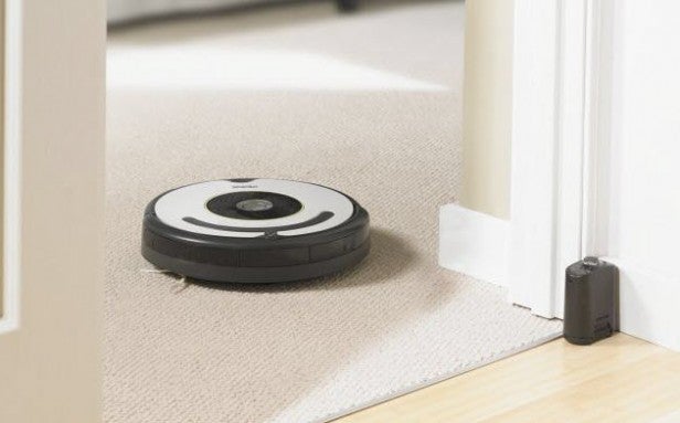 iRobot Roomba 620 vacuum cleaning carpet near doorway