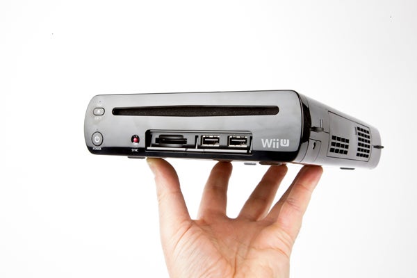 Hand holding a Wii U console showing ports and buttons.