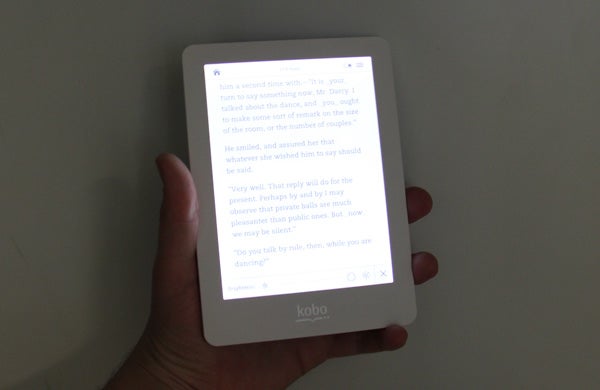 Hand holding a Kobo Glo eReader displaying text.