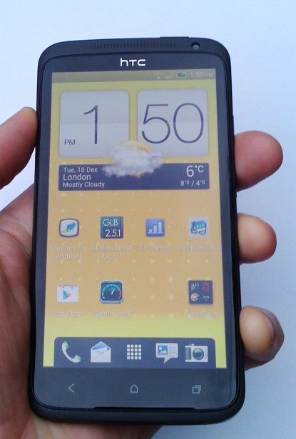 Hand holding HTC One XL smartphone displaying home screen.
