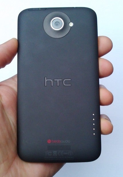 Hand holding HTC One XL smartphone showing back cover design.