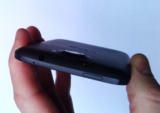 Hand holding HTC One XL smartphone showing ports and buttons