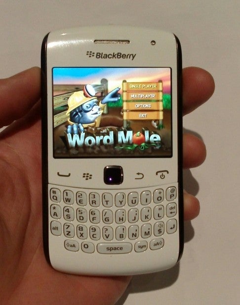 Hand holding a Blackberry Curve 9360 displaying Word Mole game.