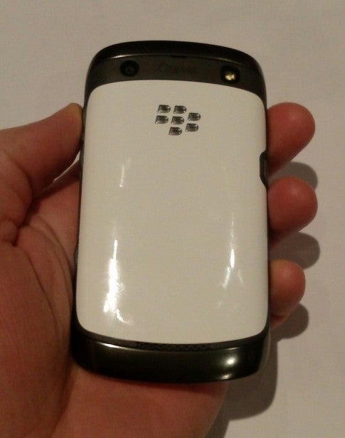 Hand holding a white Blackberry Curve 9360 smartphone.