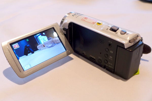 Panasonic HC-V520 camcorder with flip-out screen displaying video.