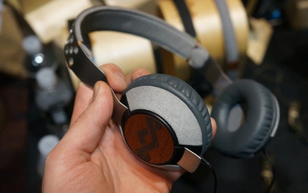 Hand holding House of Marley Liberate headphones with wooden detail.