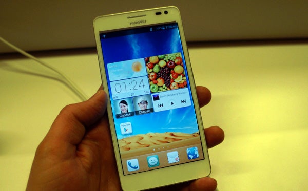 Hand holding a Huawei Ascend D2 smartphone displaying the home screen.