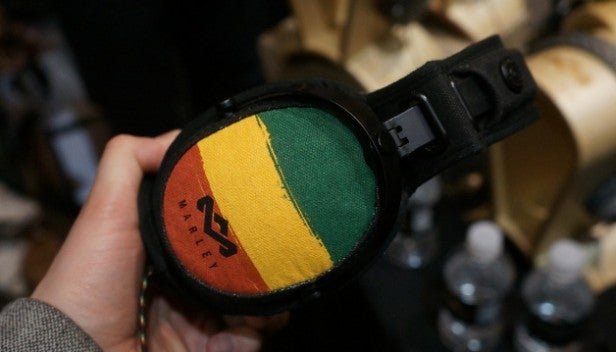 Hand holding House of Marley Rise Up headphones with Rasta colors.Close-up of House of Marley Rise Up headphones.Close-up of House of Marley Rise Up headphones ear cushion.Close-up of House of Marley headphone cable and jack.
