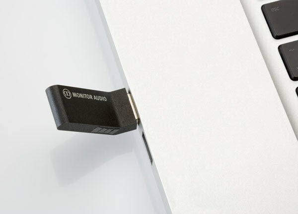 Monitor Audio WS100 wireless speaker adapter next to laptop.