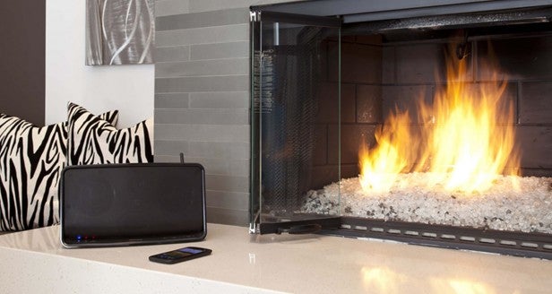 Wireless speaker on living room mantle next to fireplace.