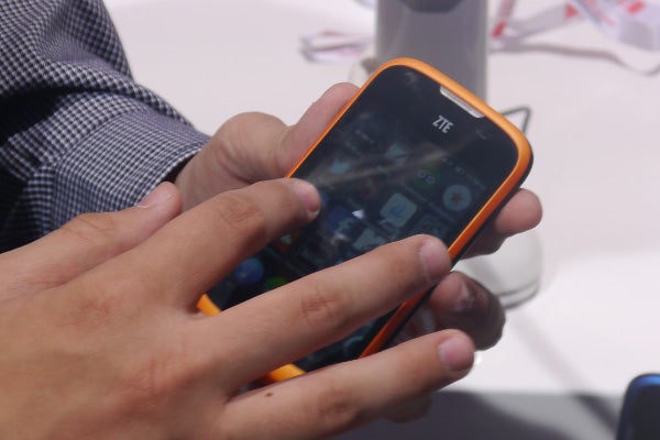 Person holding a ZTE smartphone with Firefox OS visible on the screen