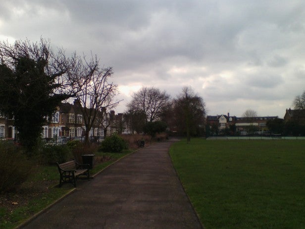 Camera test shot of a cloudy park with a pathway and bench.