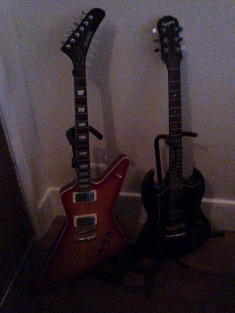 Nokia Asha 309 6Two electric guitars standing against a wall in low light.