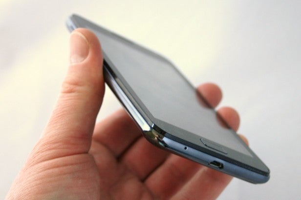 Hand holding a slim smartphone showing its side profile.
