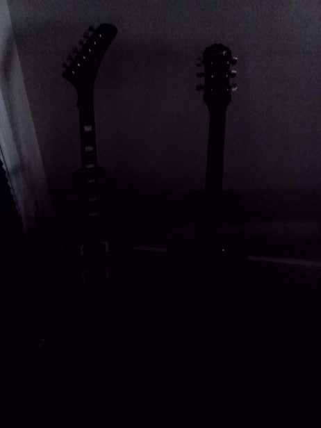 Low-light test shot of two guitars against dark background.