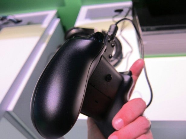 Hand holding a black Xbox One controller with a cable.Close-up of a black Xbox One controller held by a person.
