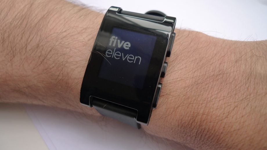 Pebble smartwatch on wrist displaying time "five eleven".