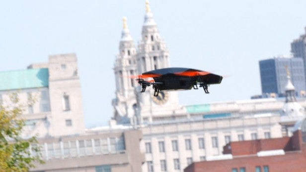 Drone in flight over urban skyline background.