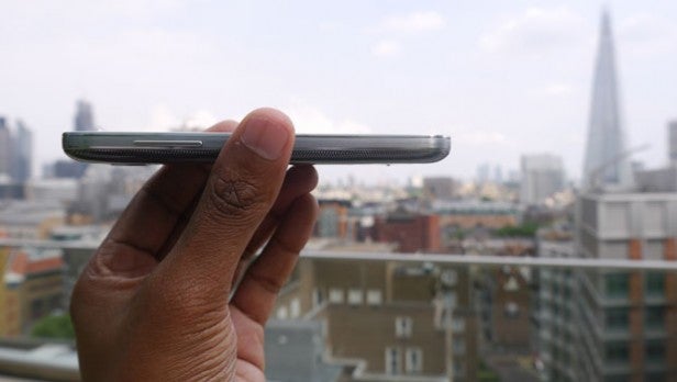 Samsung Galaxy S4 Mini smartphone on wooden surface.Hand holding Samsung Galaxy S4 Mini showing its side profile