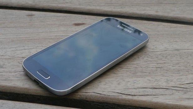 Samsung Galaxy S4 Mini smartphone on wooden surface.