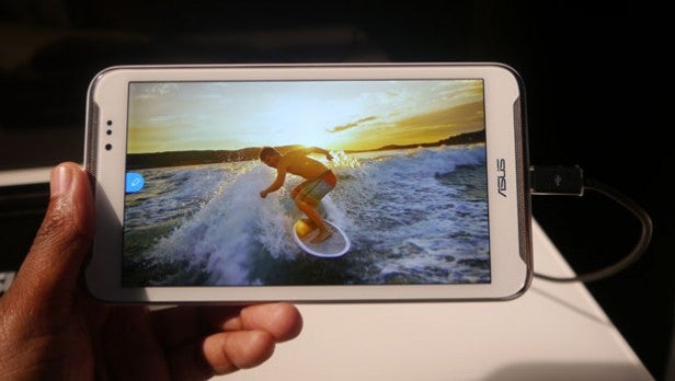 Hand holding Asus Fonepad Note 6 displaying surfer on screen.Hand holding Asus Fonepad Note 6 displaying a surfing image.