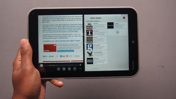 Hand holding a Toshiba Encore tablet displaying news articles.