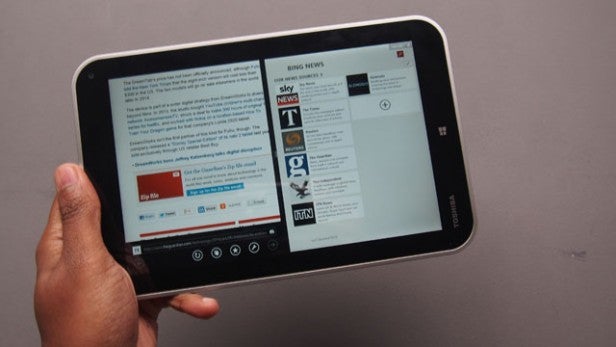 Hand holding a tablet displaying multiple applications.