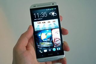 Hand holding HTC Desire 601 smartphone displaying home screen.
