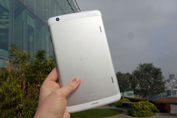 Hand holding LG G Pad 8.3 tablet outdoors.