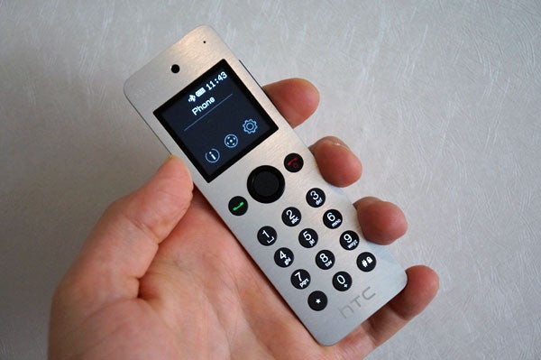 HTC Mini+ handheld device displaying phone interface.Hand holding the HTC Mini+ companion device.