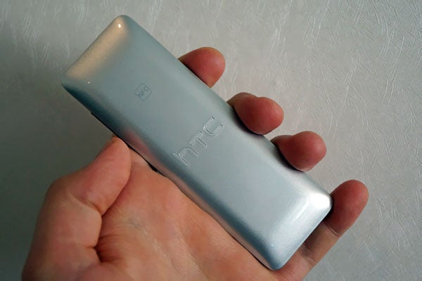 Hand holding an HTC Mini+ remote device.