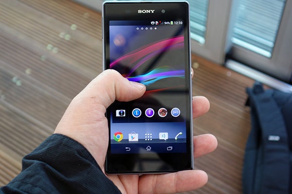 Hand holding a Sony Xperia Z1 displaying the home screen.