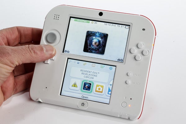 Hand holding a white Nintendo 2DS with game on screen.