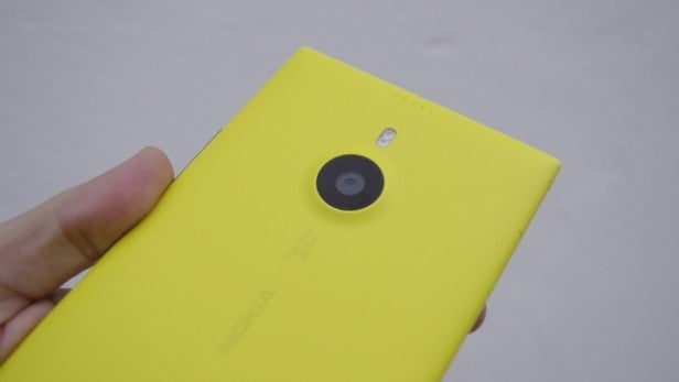 Hand holding a yellow Nokia smartphone with camera lens visible.