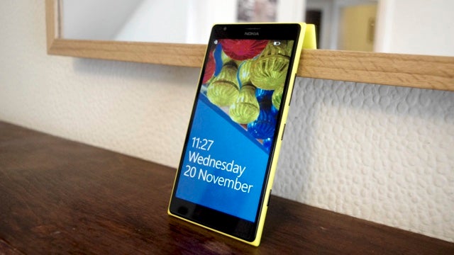 Nokia Lumia 1520 smartphone with yellow case on wooden surface.