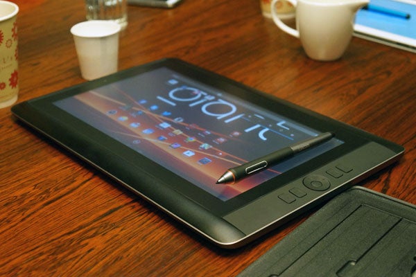 Wacom Cintiq Companion tablet with pen on wooden table.