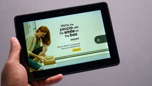 Hand holding Amazon Kindle Fire HDX displaying an ad.