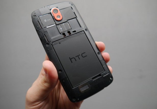 Hand holding an HTC smartphone without its back cover.